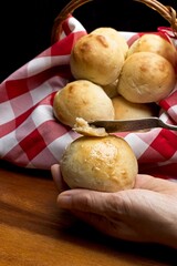 Holding a roll and spreading on butter.