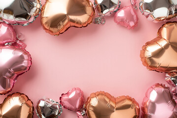 Valentine's Day concept. Top view photo of heart shaped pink silver and golden balloons on isolated pastel pink background with blank space in the middle