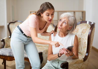 Two multigenerational women look at phone screen