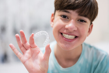 Teenager boy wear simulator orthodontic silicone invisible leveling braces for teeth.  Dental...