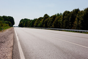 New asphalt road with markings and road signs in the sun's rays