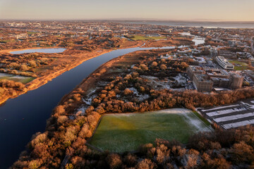 River Corrib and Galway city at winter. Snow on a sport ground. Aerial view. Calm and peaceful mood.