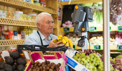 Portrait of a positive male salesperson at the checkout counter at a grocery supermarket