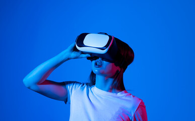 Young woman in virtual reality VR glasses playing a video games.