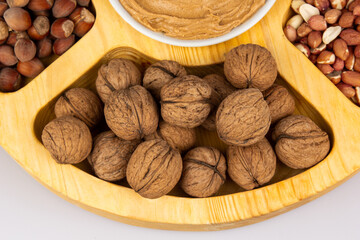 Peanuts, walnuts and hazelnuts in a wooden box with compartments. Three different types of nuts, shelled and shelled, decorative assortment and ready to eat. Closeup, isolated, from above.