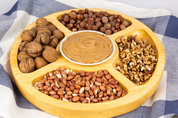 Peanuts, walnuts and hazelnuts in a wooden box with compartments. Three different types of nuts,...