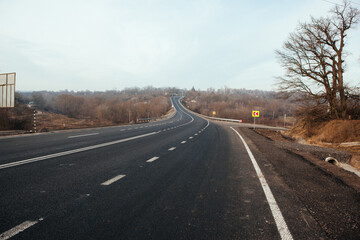 Fototapeta premium New asphalt road with markings and road signs in the sun's rays