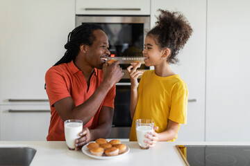 Happy Black Father And Daughter Eating Snacks And Having Fun In Kitchen
