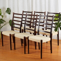 Midcentury modern dining room chairs. 6 vintage rosewood chairs with fabric seats. Product photograph in front of a white curtain with houseplants.