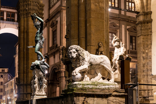 Statues of a Lion and "Perseus with the Head of Medusa" housed in the Loggia dei Lanzi, by night, dark atmosphere, in Signoria square, Florence city center, Italy