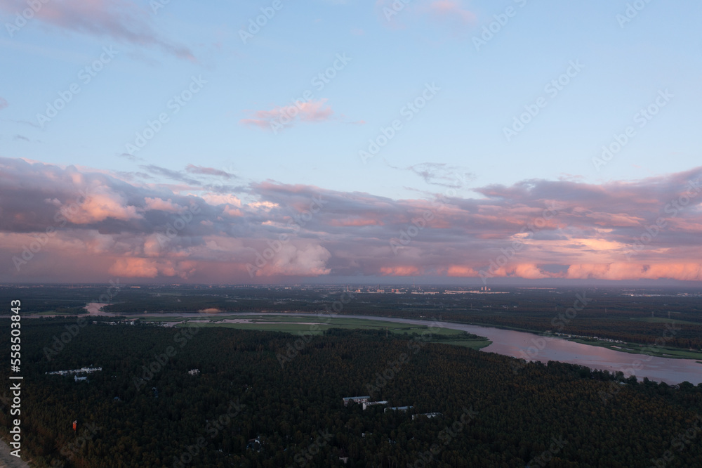 Poster a river running through a lush green forest under a cloudy blue sky with pink and white clouds above