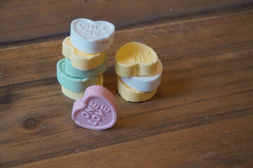 Pastel Colored Novelty Heart Candies in Stacks on Medium Brown Wood Panels