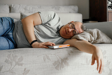 Portrait of smiling middle-aged man lying with closed eyes, stretching hand, pretending sleeping...
