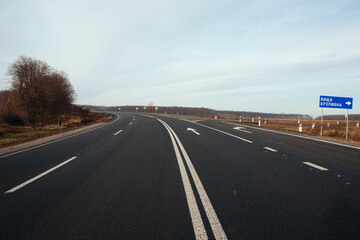 New asphalt road with markings and road signs in the sun's rays