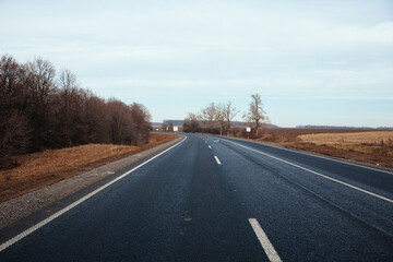 New asphalt road with markings and road signs in the sun's rays