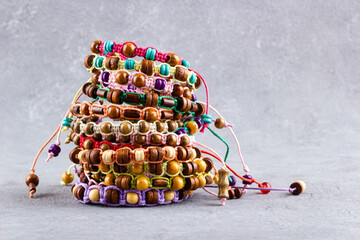 A stack of bracelets made of wooden beads and natural cord on a gray background.