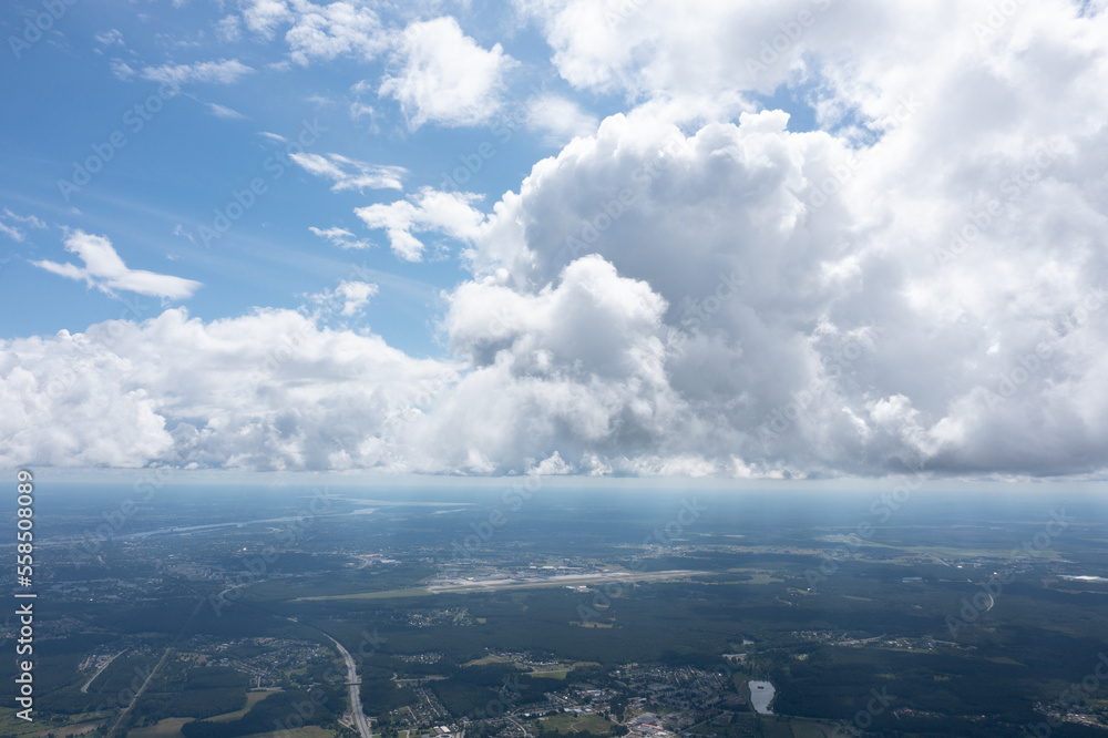 Poster a view of the sky from an airplane window with a lot of clouds in the distance and a river running t