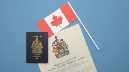 A Canadian passport on a Canadian Flag and a Canadian Citizenship Certificate against a solid light blue background