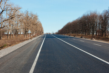 Fototapeta premium New asphalt road with markings and road signs in the sun's rays