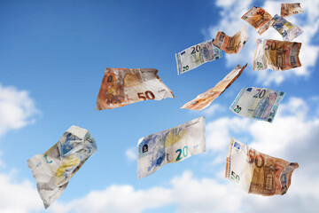 Flying money coming down from the blue sky, twenty and fifty paper banknotes in euro currency,...