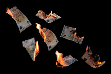 Burning money, twenty and fifty euro banknotes with flames flying isolated against a black...