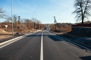 New asphalt road with markings and road signs in the sun's rays