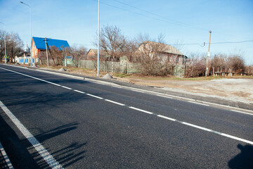 New asphalt road with markings and road signs in the sun's rays
