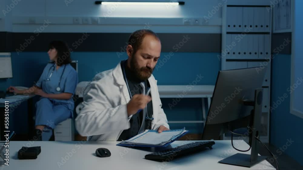 Aufkleber practitioner doctor standing at desk looking at data expertise on computer comparing with medical pa