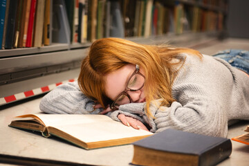 Teen girl with red hair and glasses sleeping while studying.