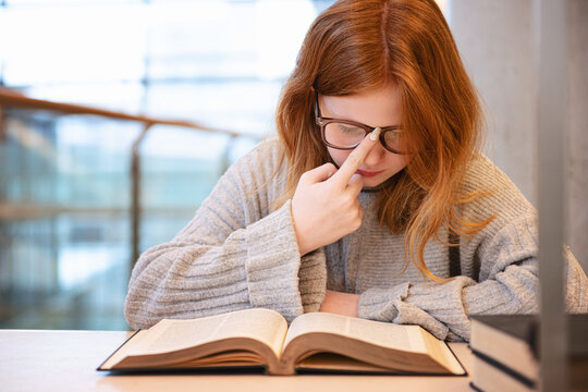 Teen girl with red hair studying at urban library.