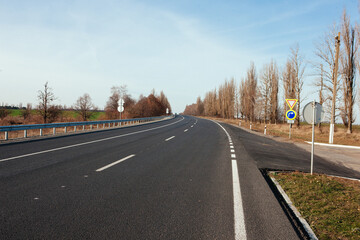 New asphalt road with markings and road signs in the sun's rays