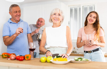 Happy family with elderly parents preparing lunch in a modern kitchen