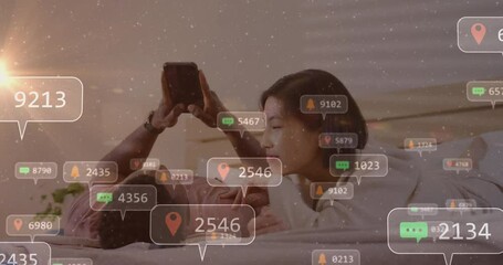 Animation of social media icons with numbers over diverse couple using smartphone - Powered by Adobe