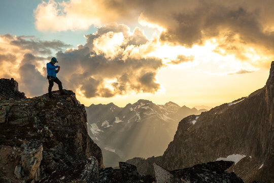 Mountain climber photographing view at sunset in North Cascade Mountain Range, Chilliwack, British Columbia, Canada