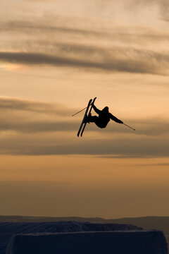 Jumping skier silhouetted at sunset.