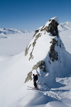 Telemark skier looks over backcountry on sunny blue sky day.