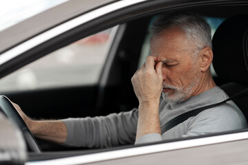 Overworked 60-70 years old, senior man, taxi driver feeling headache and tired while driving car 