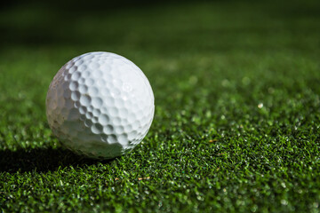 Close up of a gold ball on turf next to a hole