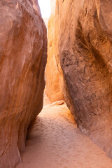 A narrow slot through a desert canyon with a sandy floor