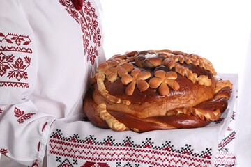 Woman with korovai on white background, closeup. Ukrainian bread and salt welcoming tradition