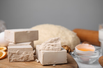 Blocks of compressed yeast and ingredients on wooden table, closeup