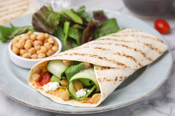 Delicious hummus wrap with vegetables on table, closeup