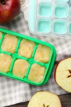 Apple puree in ice cube tray with ingredients on table, flat lay