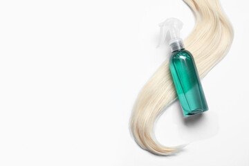 Spray bottle with thermal protection and lock of blonde hair on white background, flat lay. Space for text