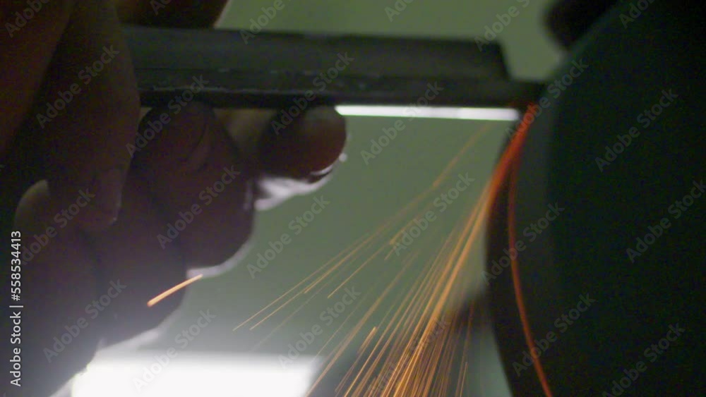 Poster slow motion shot of sparks flying off of a chisel being sharpened on a grindstone