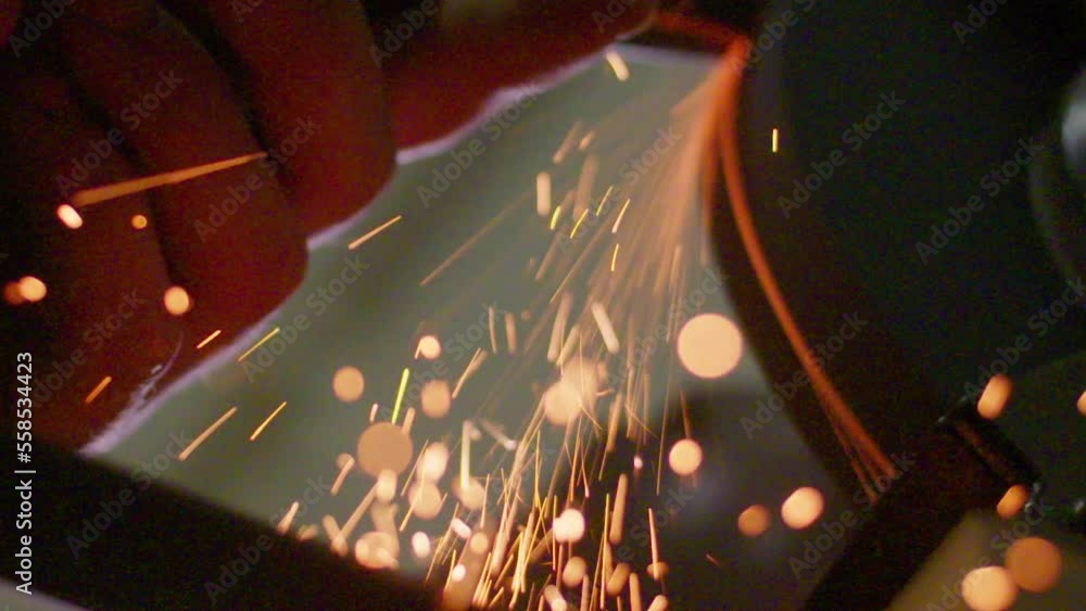 Poster slow motion shot of sparks flying off of a chisel being sharpened on a grindstone