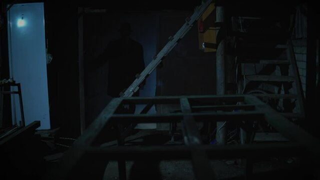 Old garage with blue light. Atmosphere dark place full of smoke. Strang and mystery man in black coat and black hat is walking 