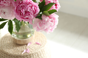 Bouquet of beautiful peonies on pouf indoors, closeup. Space for text