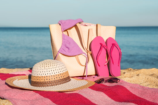 Towel with bag and beach accessories on sand near sea