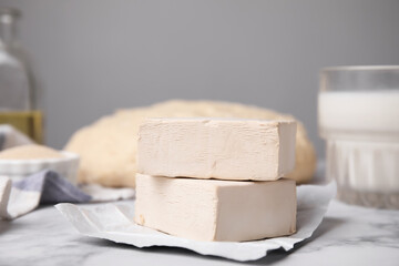 Blocks of compressed yeast on white marble table, closeup